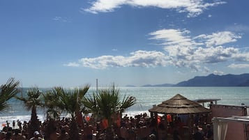 Een privéstrand, ligstoelen aan het strand, parasols, een strandbar