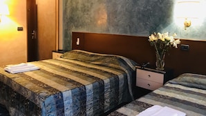 Ein Hotelzimmer mit zwei Betten, einem Nachttisch, einer Vase mit Blumen und einer strukturierten Wand.