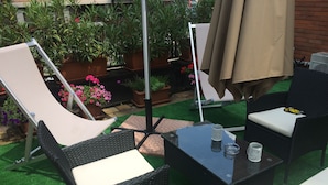 Ein Patio im Freien mit Korbmöbeln, einem Tisch und Blumentöpfen.