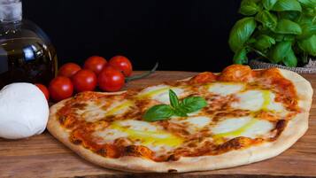 Pizza met kaas en basilicum op een houten ondergrond.