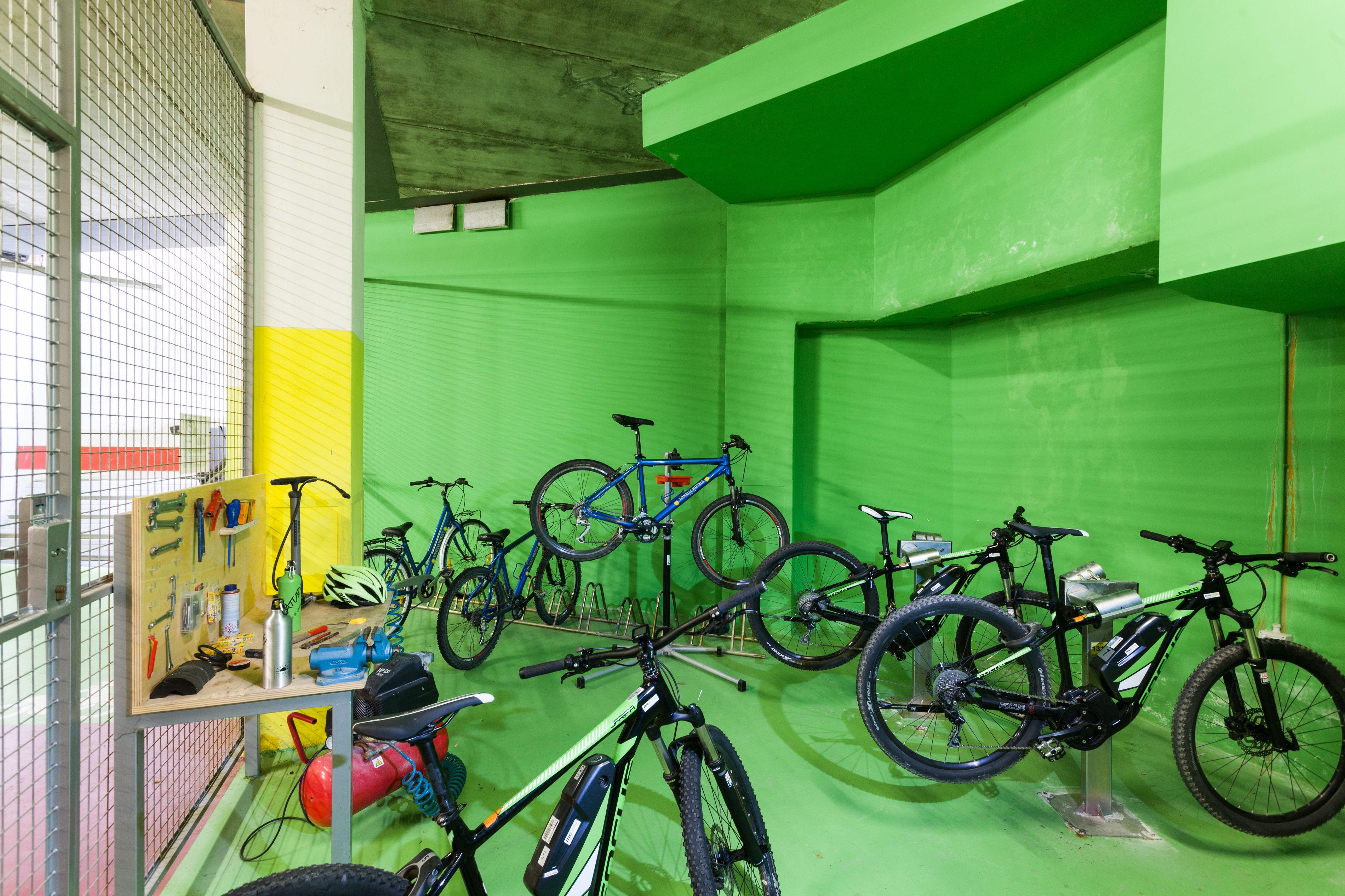 Zona de alquiler de bicicletas con varias bicicletas y un tablero de anuncios con herramientas.