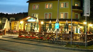 A hotel with outdoor seating, a bicycle parked in front, and a sign indicating a parking area. - Hotel Risnjak (Delnice)