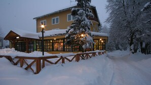 A hotel with a snow-covered exterior, wooden deck, and a visible entrance. - Hotel Risnjak (Delnice)