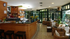 A bar area with a counter, stools, and a seating area with wicker furniture. - Hotel Risnjak (Delnice)