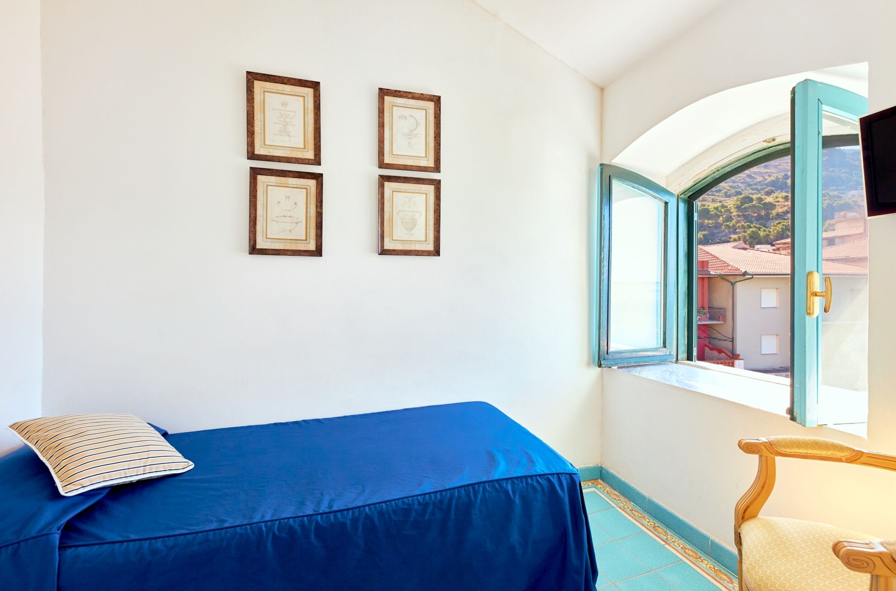 A room with a blue sofa, a wooden chair, and a window with a view of buildings.