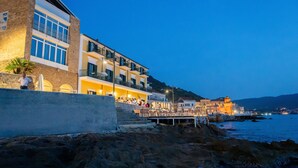A coastal building with multiple balconies and a dock extending into the water. - Villa Sirio (Castellabate)