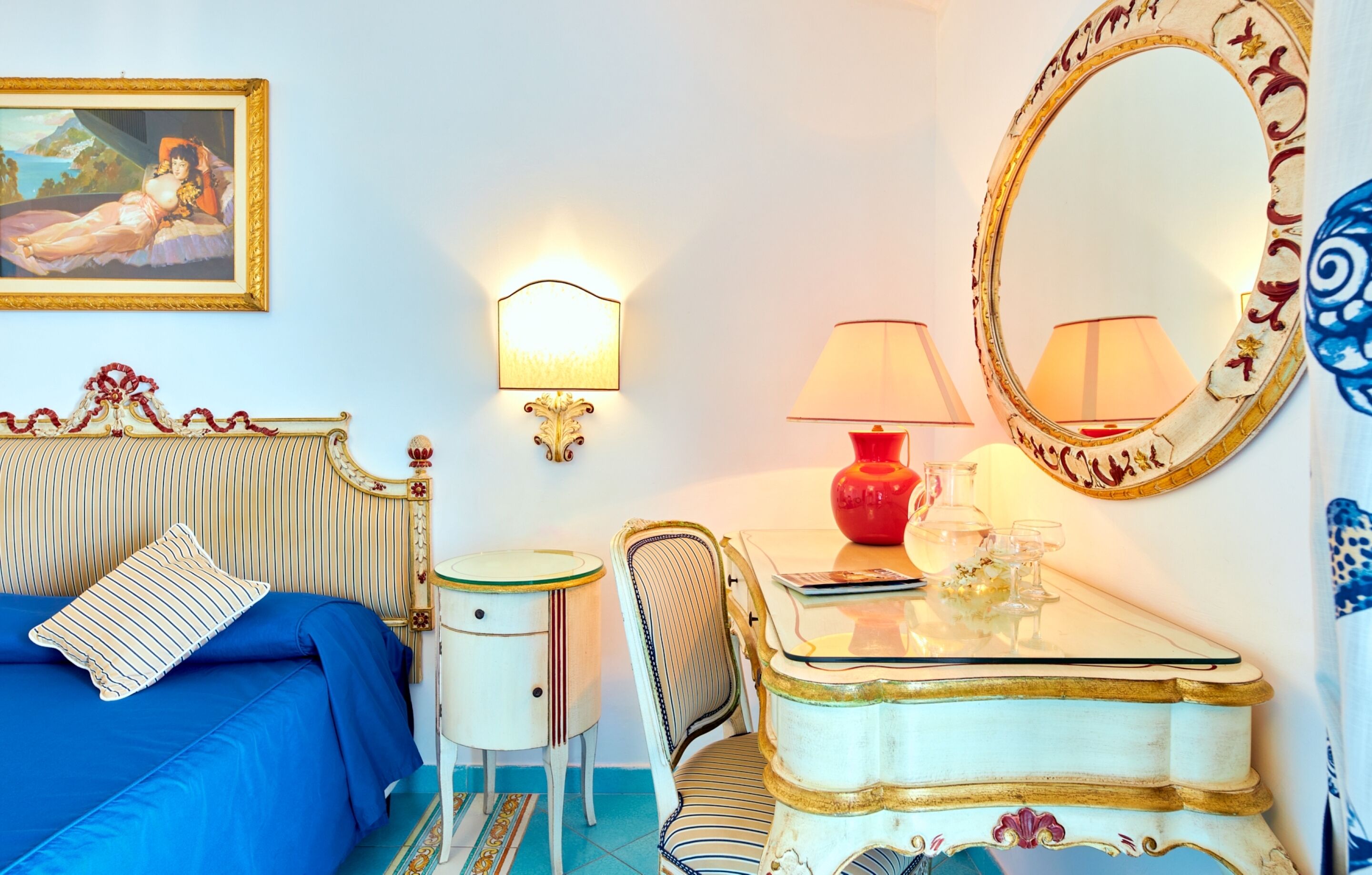 Un dormitorio con cama, mesita de noche, silla, cómoda, espejo y lámpara de pared.