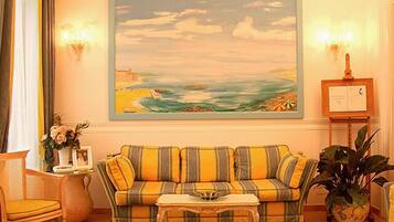 A living room with a striped sofa, a small table, and a painting of a beach scene.