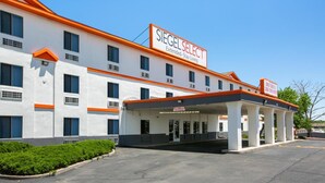 A hotel with a white facade, orange accents, and a covered parking area. - Siegel Select Albuquerque (Albuquerque)