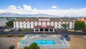 A hotel with a swimming pool, outdoor seating, and a mountain backdrop. - Siegel Select Albuquerque (Albuquerque)
