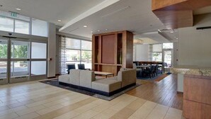 A spacious lobby with a seating area, a wooden reception desk, and large windows allowing natural light. - HYATT house Chicago/Naperville/Warrenville (Warrenville)