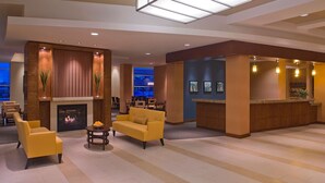 A spacious lobby with a fireplace, yellow sofas, and a reception desk. - HYATT house Chicago/Naperville/Warrenville (Warrenville)