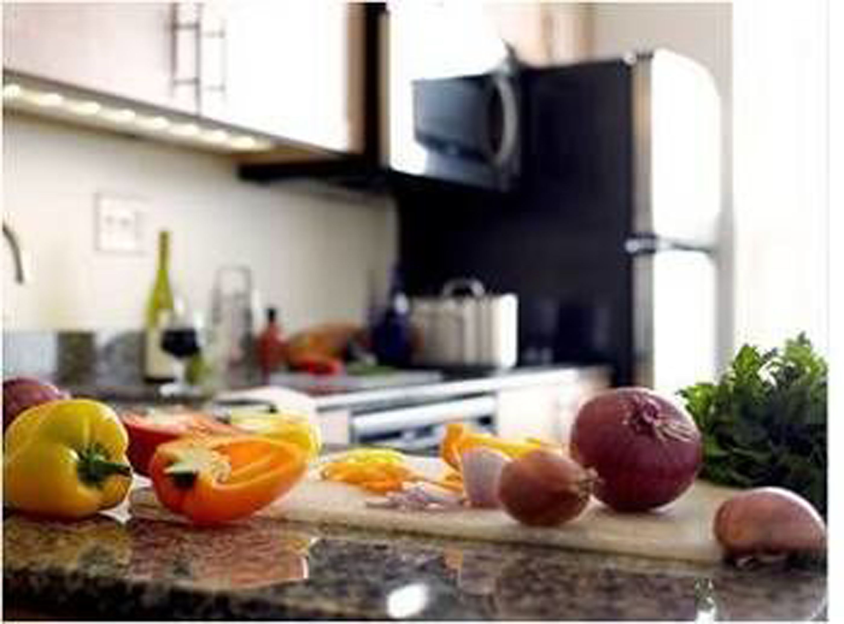 Una encimera de cocina con verduras y un microondas al fondo.