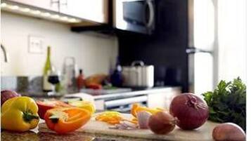 Una encimera de cocina con verduras y un microondas al fondo.