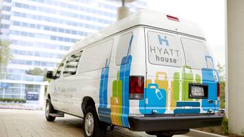 En hvid varevogn med farverige bagageillustrationer og teksten "HYATT house" på bagsiden.