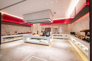 A modern kitchen with marble countertops, a central island with a coffee machine, and red ambient lighting.