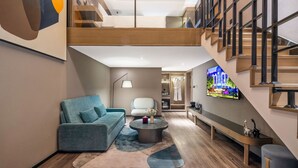 A modern interior with a loft-style staircase, a living area with a sofa and coffee table, and a TV mounted on the wall. - Mercure Harbin Central Street Sophia Church (Harbin)