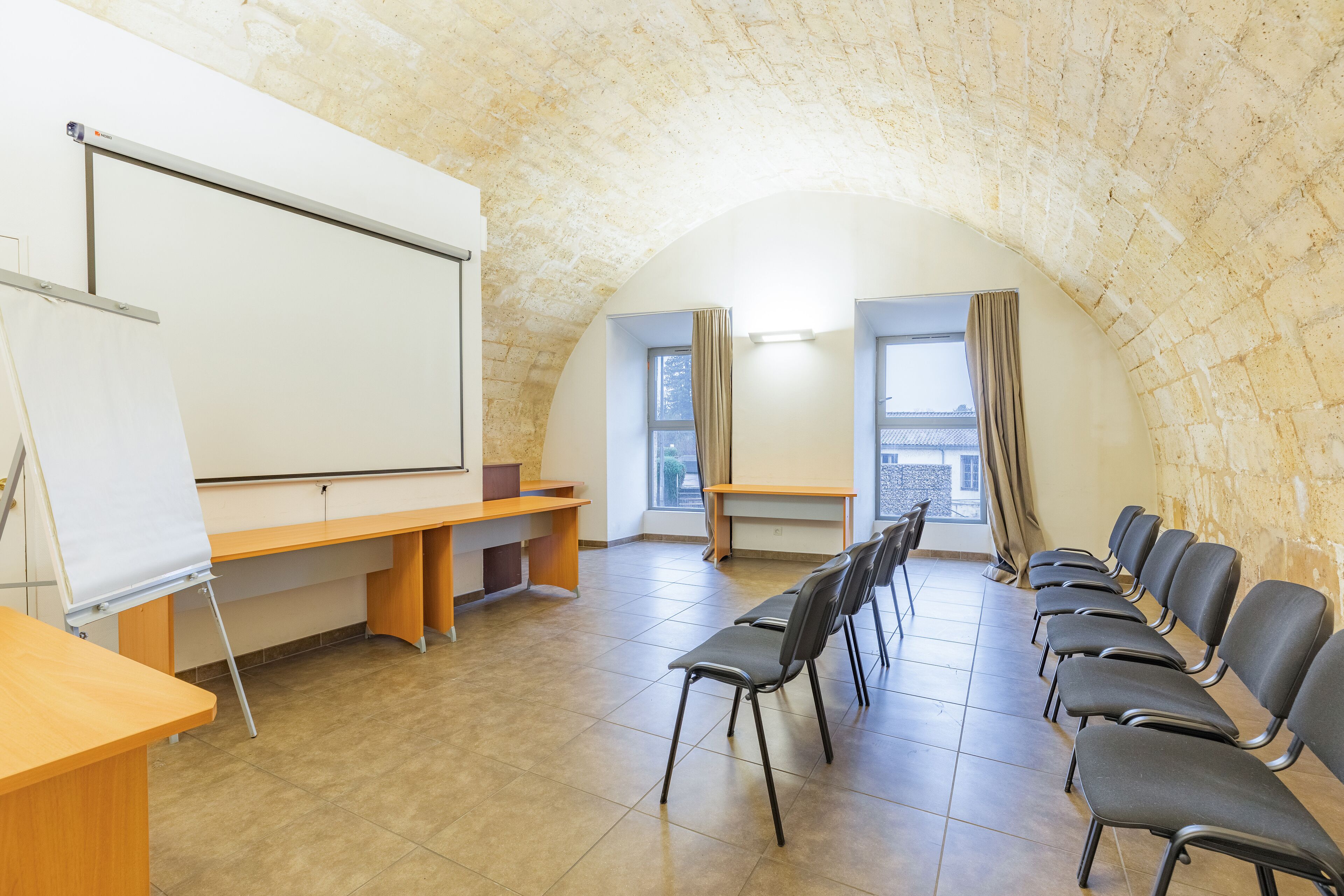 A conference room with a whiteboard, a projector, and a row of chairs facing a whiteboard.