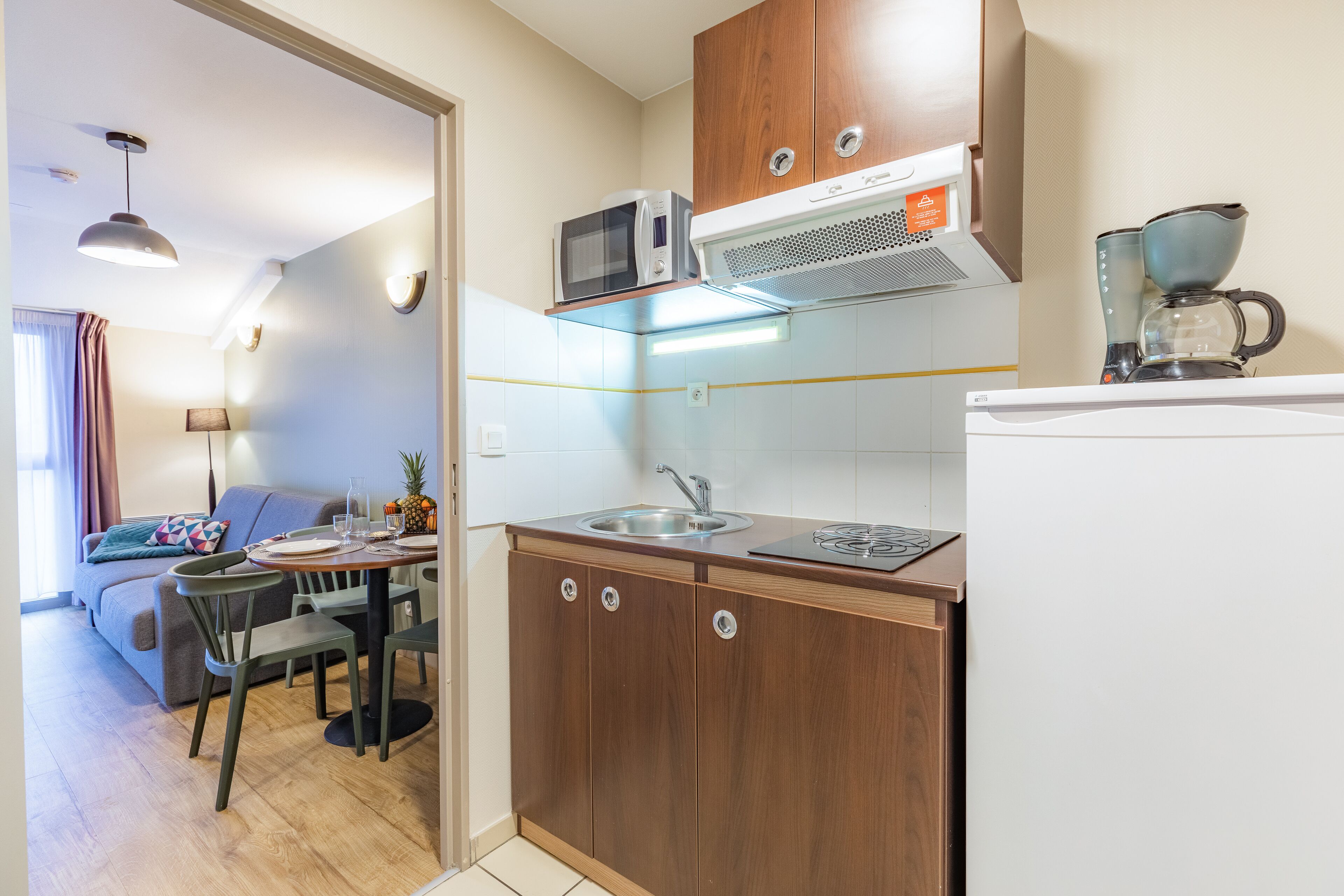 A compact kitchen with a microwave, stove, and coffee maker.