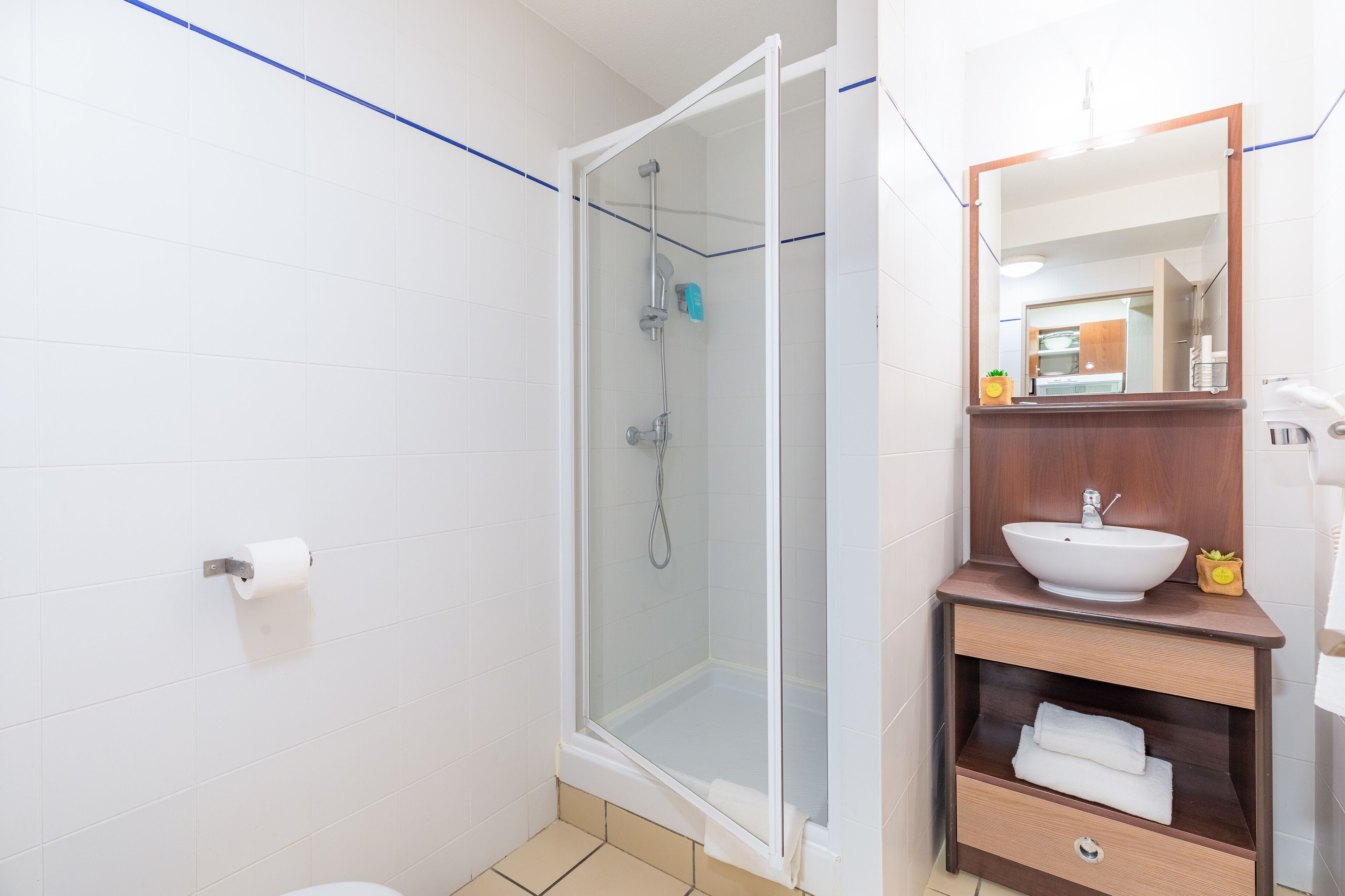 A modern bathroom with a glass-enclosed shower, a white sink, and a wooden vanity.