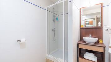 A modern bathroom with a glass-enclosed shower, a white sink, and a wooden vanity.