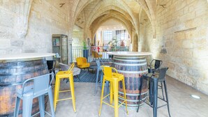 An interior with stone arches, a bar area with stools, and a view into another room. - Appart'City Classic  Angoulême Centre (Angouleme)