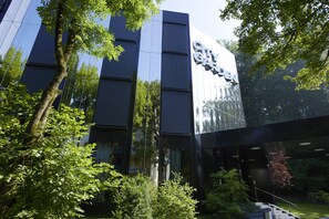 A modern building with a reflective glass facade and a sign that reads "City Garden." - City Garden Hotel (Zug)