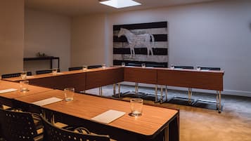 A conference room with a long wooden table, chairs, and a large abstract painting on the wall.