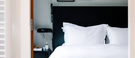 A hotel room with a large bed, a bedside table with a lamp, and two framed pictures on the wall.
