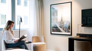 Une chambre d’hôtel avec un grand lit, un bureau, une chaise, une télévision et une fenêtre avec des rideaux.