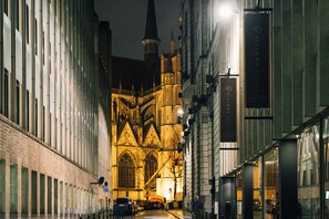 Una catedral de arquitectura gótica, una torre de campanas y un edificio moderno con un letrero de Pilows Hotels.