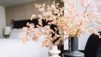 Een kamer met een bed, een witte vaas met roze bloemen en een grijze vaas.