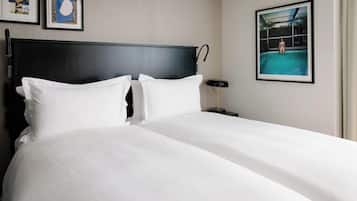 Habitación de hotel con una cama grande, dos almohadas, cabecero, mesita de noche, lámpara y cuadros en la pared.