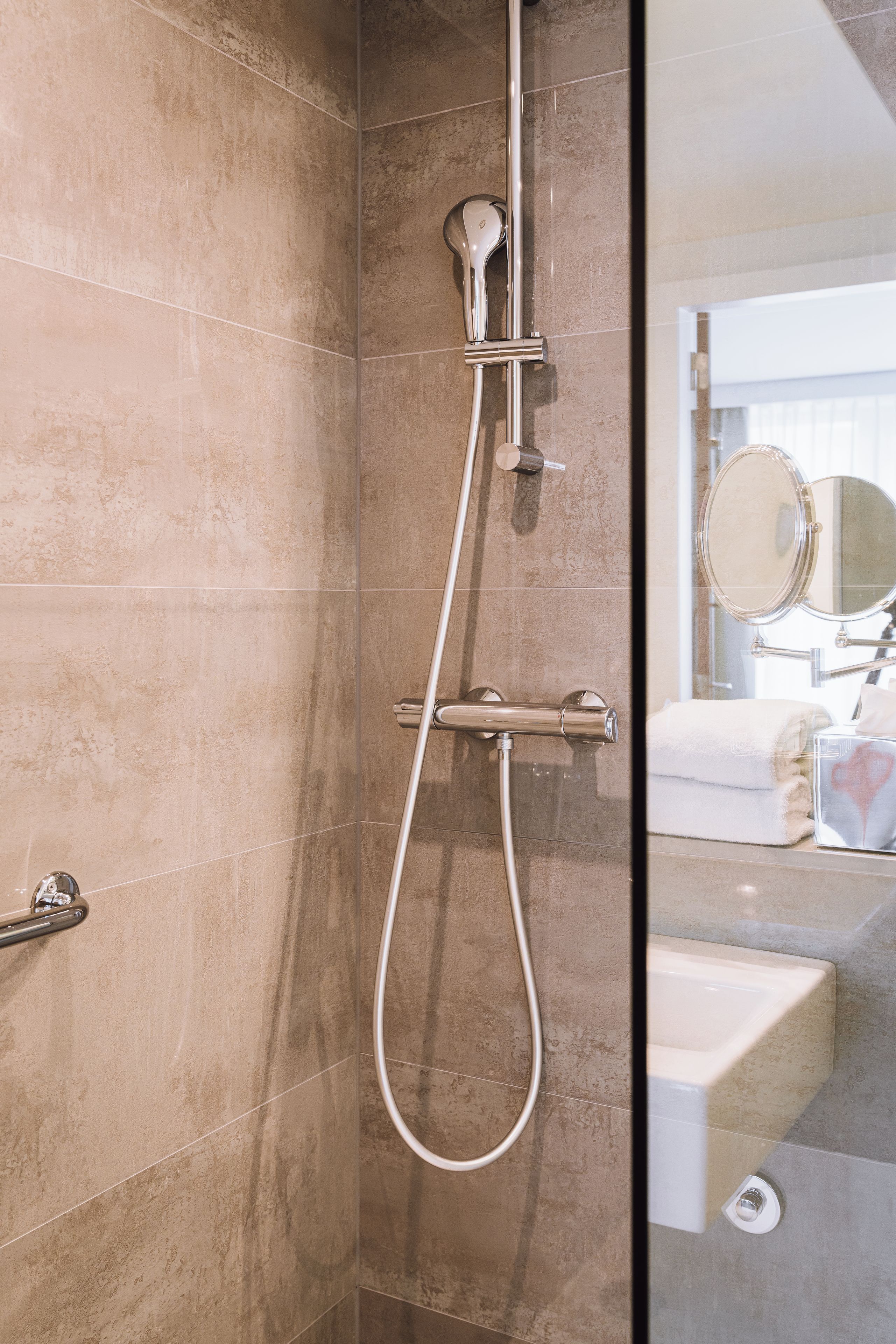 A bathroom with a shower, a mirror, and a towel.