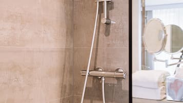 Een badkamer met een douche, spiegel en handdoek.