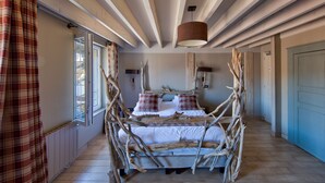 A rustic bedroom with a bed made of natural materials, a window with curtains, and a wooden ceiling. - Hôtel Le Grand Cerf & Spa Nuxe (Lyons-la-Foret)