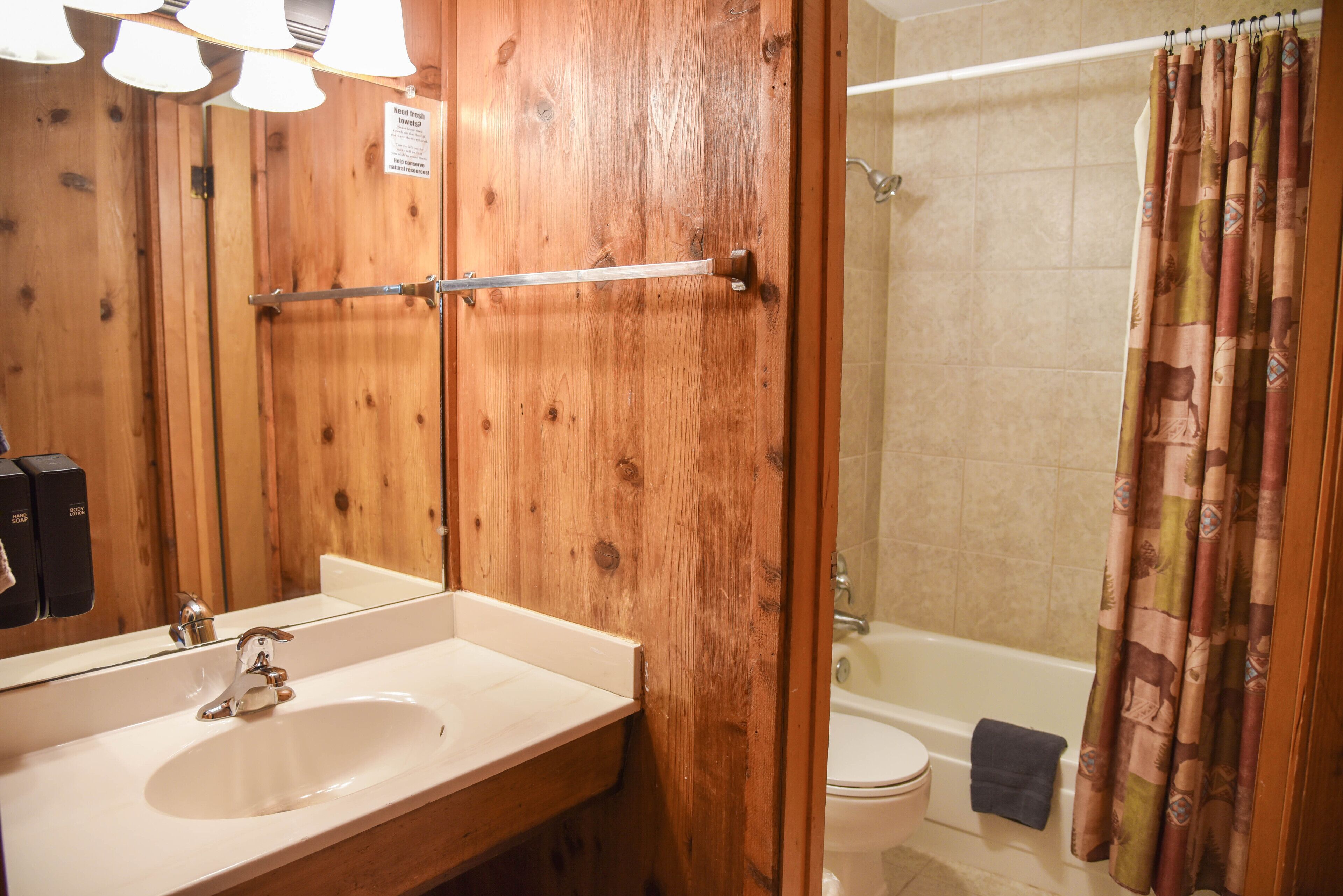 Une salle de bain en bois avec un lavabo, un miroir et un rideau de douche.