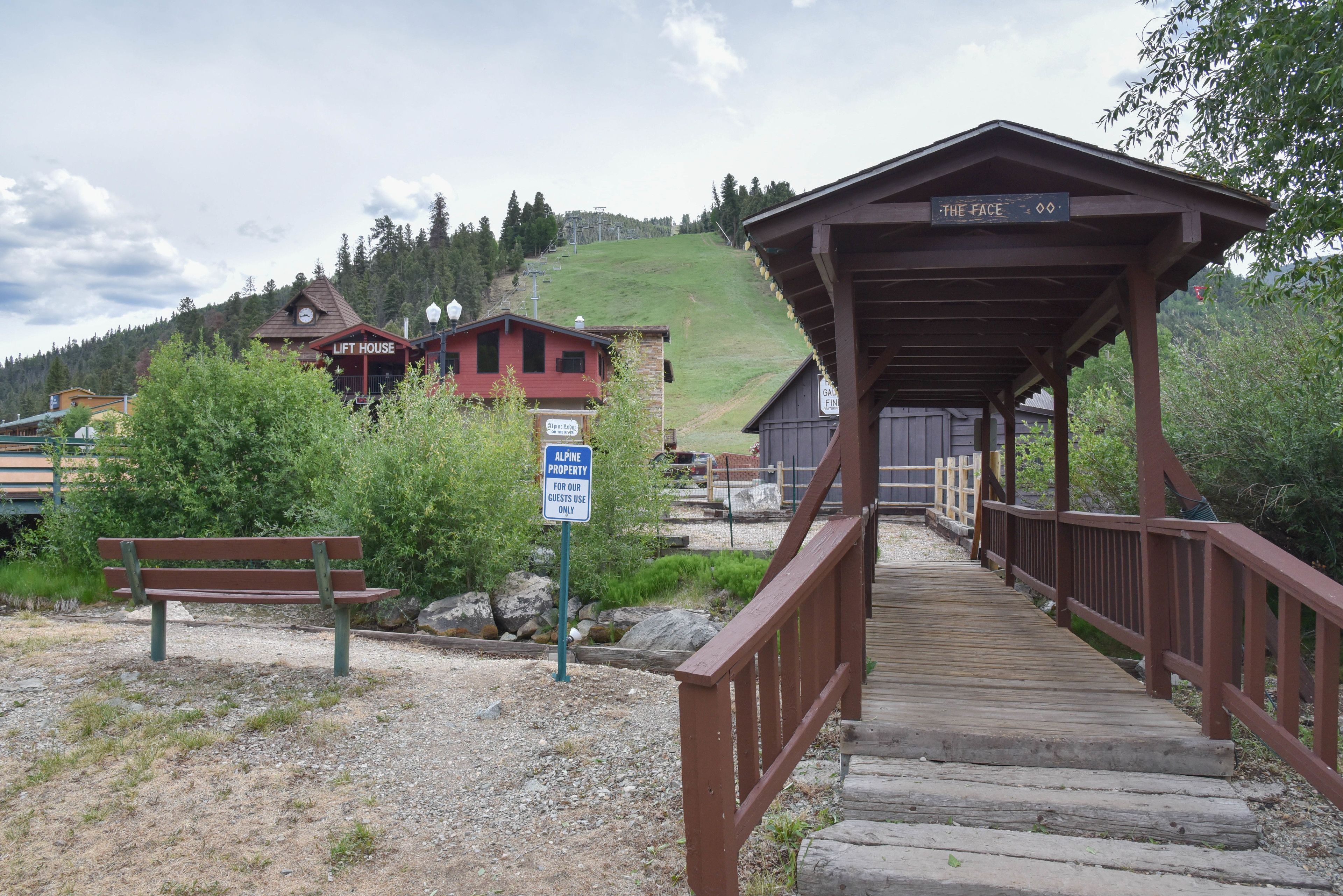 Eine Holzbrücke führt zu einem Gebäude mit der Aufschrift 'LIFT HOUSE'. Ein Schild kennzeichnet es als reinen Gastbereich.