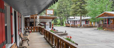 A wooden deck with benches, a sign for Alpine Lodge Office, and buildings in the background.