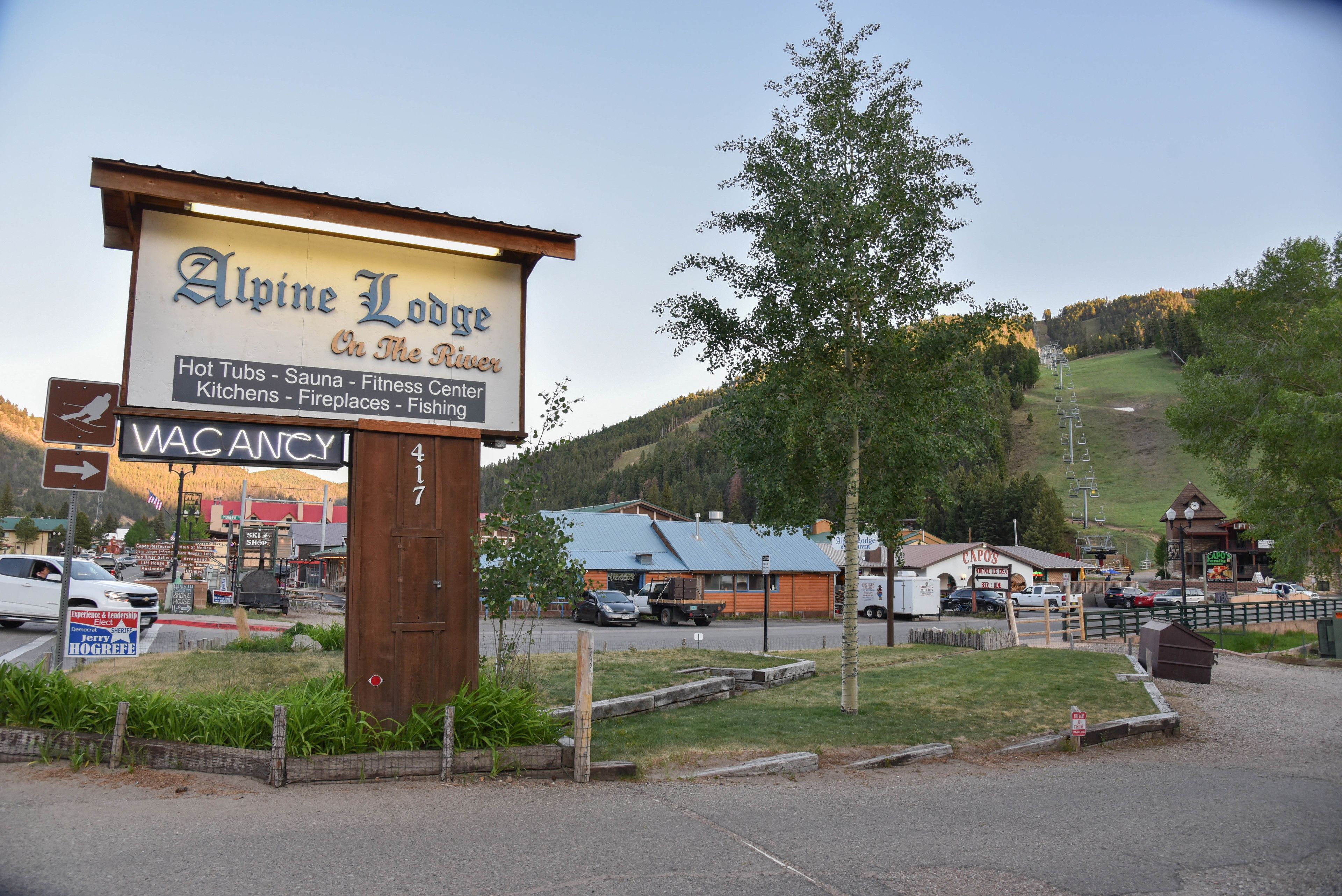 A sign for Alpine Lodge with amenities like hot tubs, a sauna, fitness center, kitchens, fireplaces, and fishing.