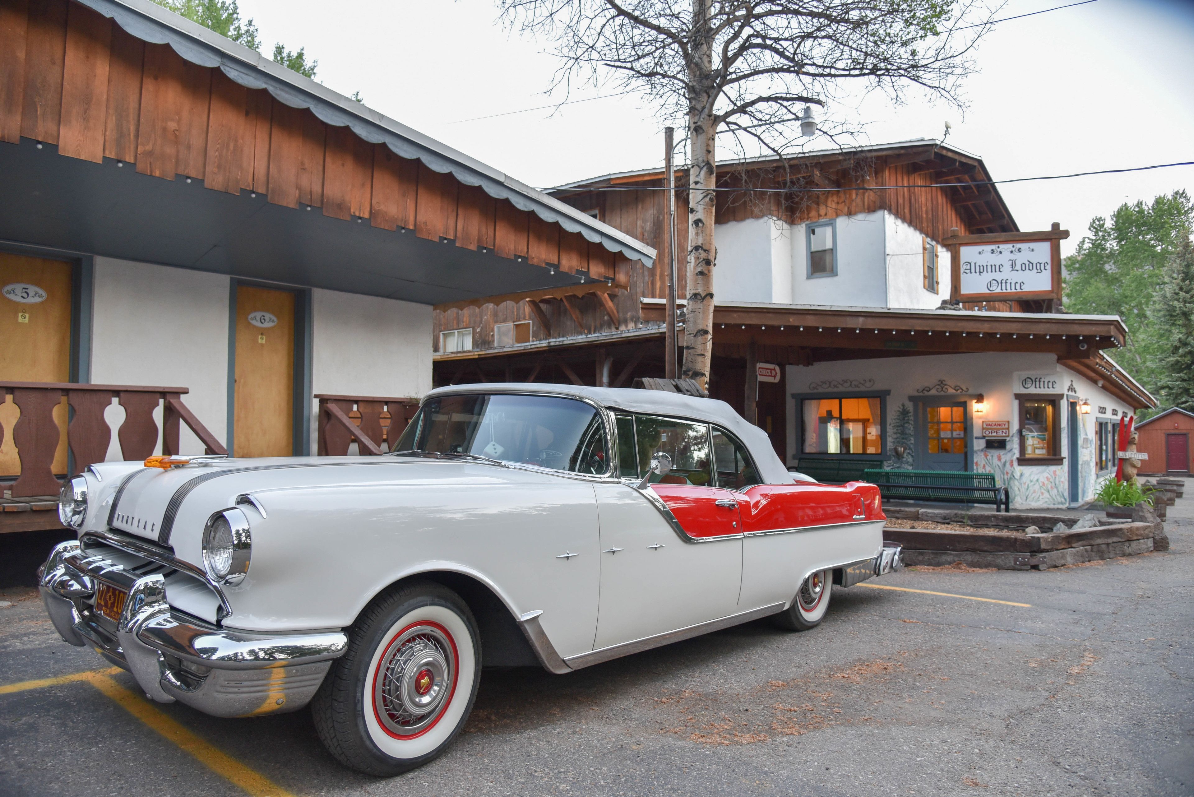 Un coche antiguo blanco y rojo estacionado frente a un edificio con un letrero que dice 