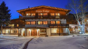 Een tweelaags vakantiehuis met een balkon en een bord waarop staat 'Alpine Lodge'.