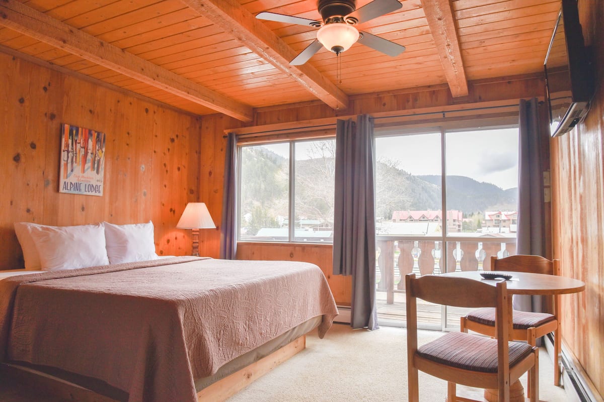 A wooden room with a bed, a table, and chairs.