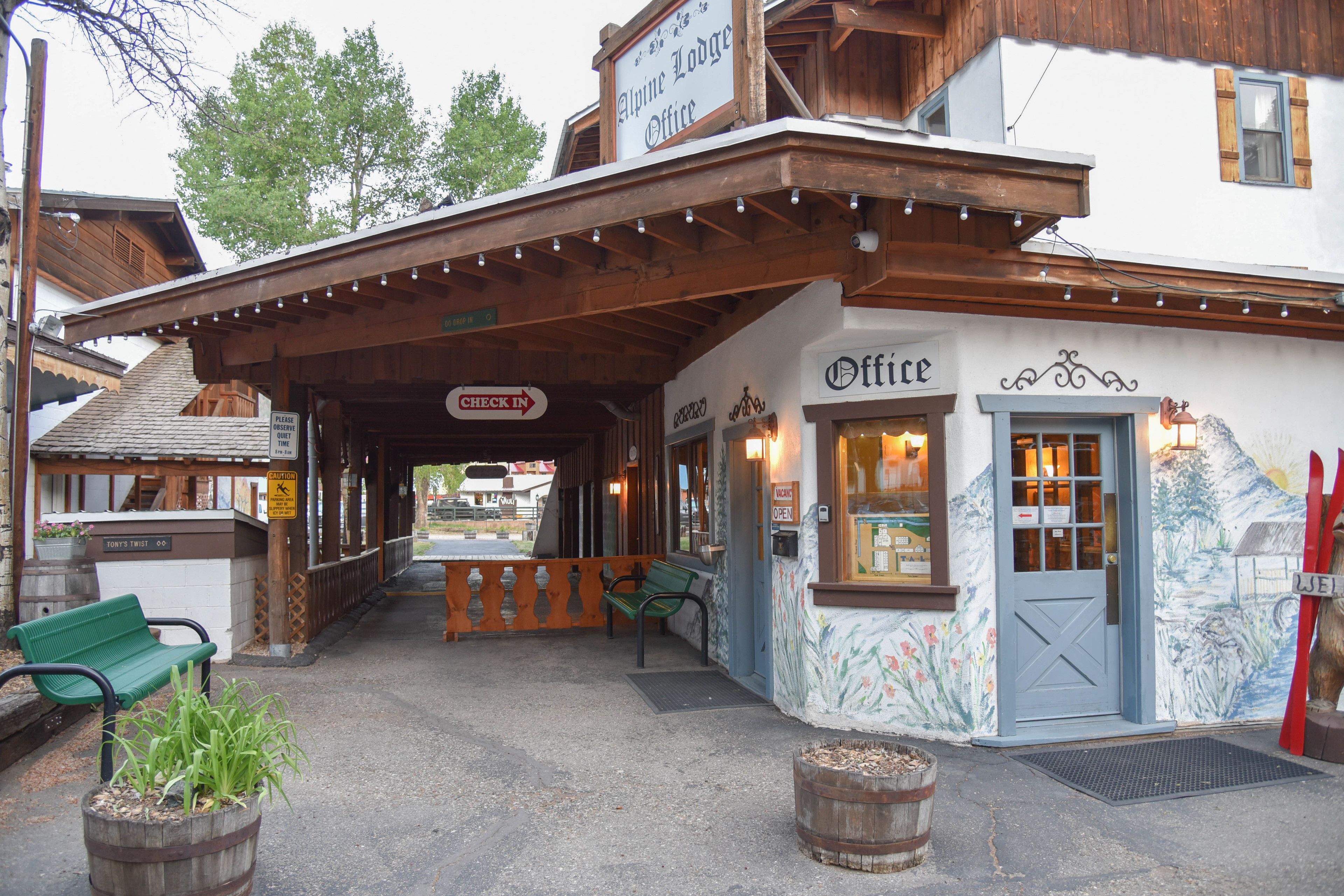 A lodge office with a check-in sign, outdoor seating, and a wooden bench.