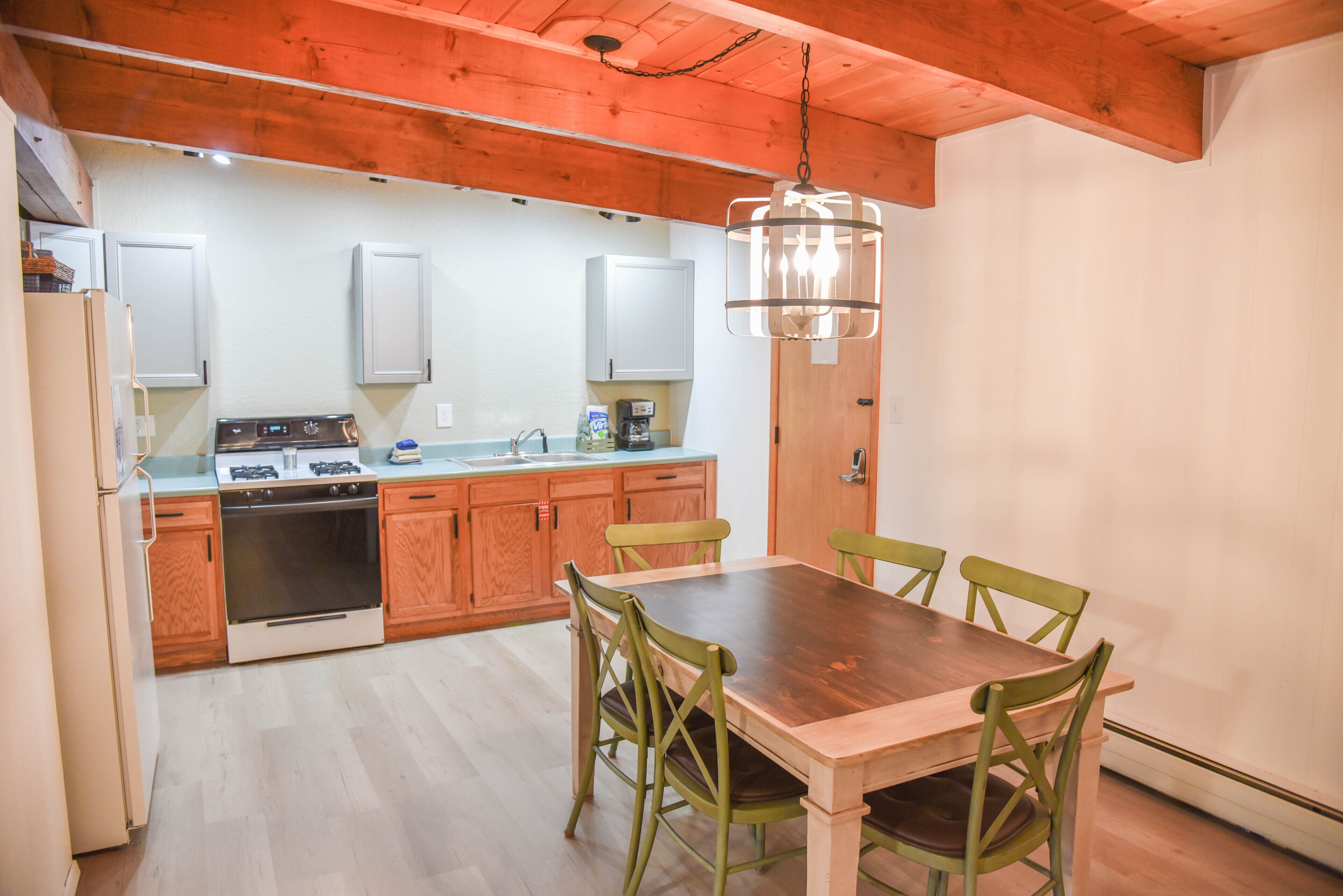 A kitchen with wooden cabinets, a stove, and a dining table with chairs.