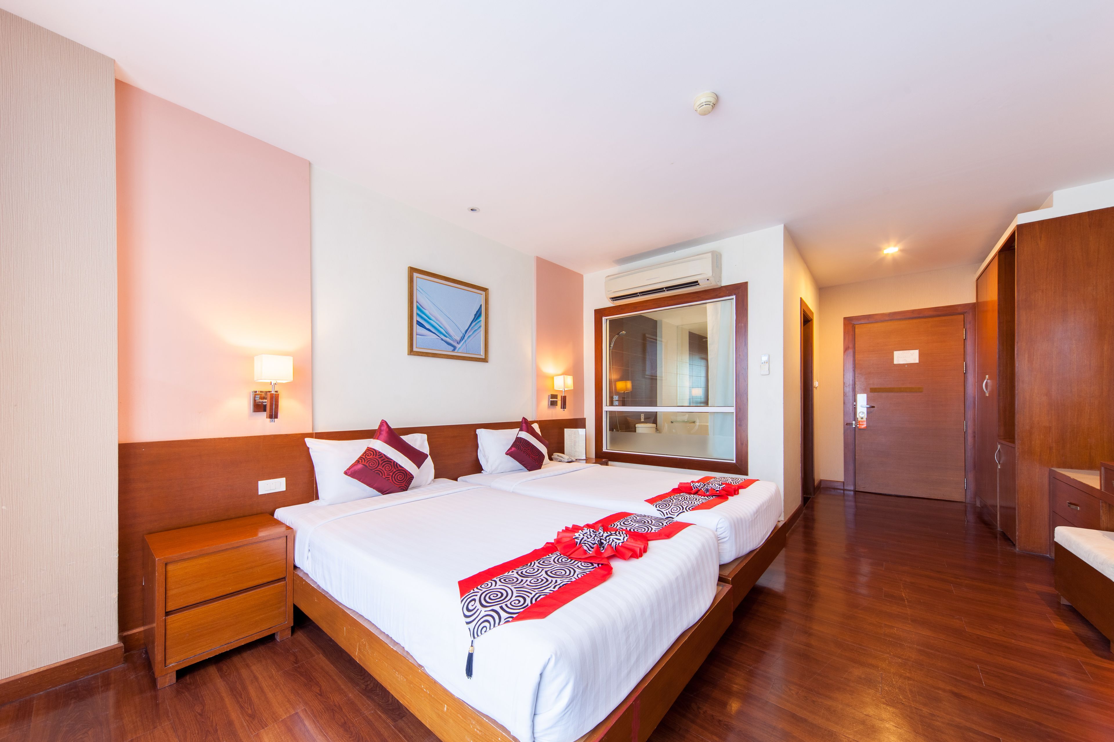A hotel room with a large bed, bedside tables, a wardrobe, and a mirror.