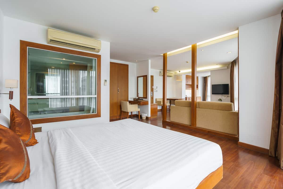 A hotel room with a large bed, a desk, a sofa, and a TV.