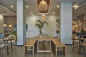 A spacious dining area with a long wooden table set for a meal, surrounded by wicker chairs.