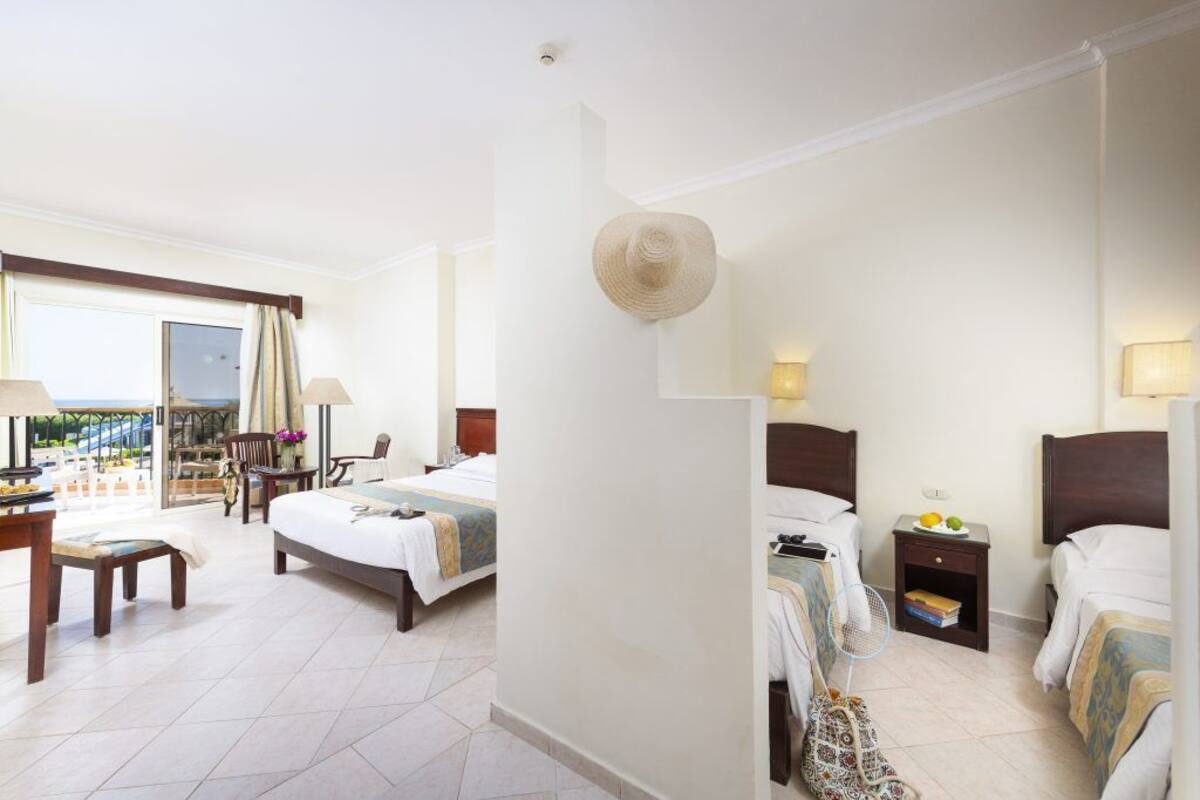 A hotel room with a balcony, a bed, a desk, and a chair.