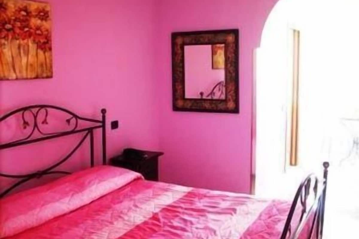 Una habitación con una cama, un cuadro y un espejo en la pared.